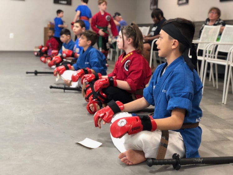 kids sitting in a line in karate gear