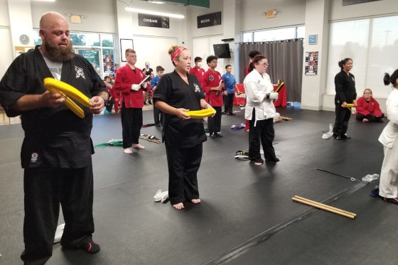 adult karate class with students holding karate props